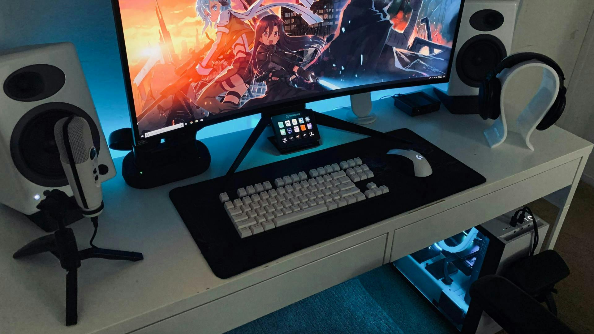 A white gaming setup with gaming PC, ultrawide monitor, headset, streaming microphone and white speakers