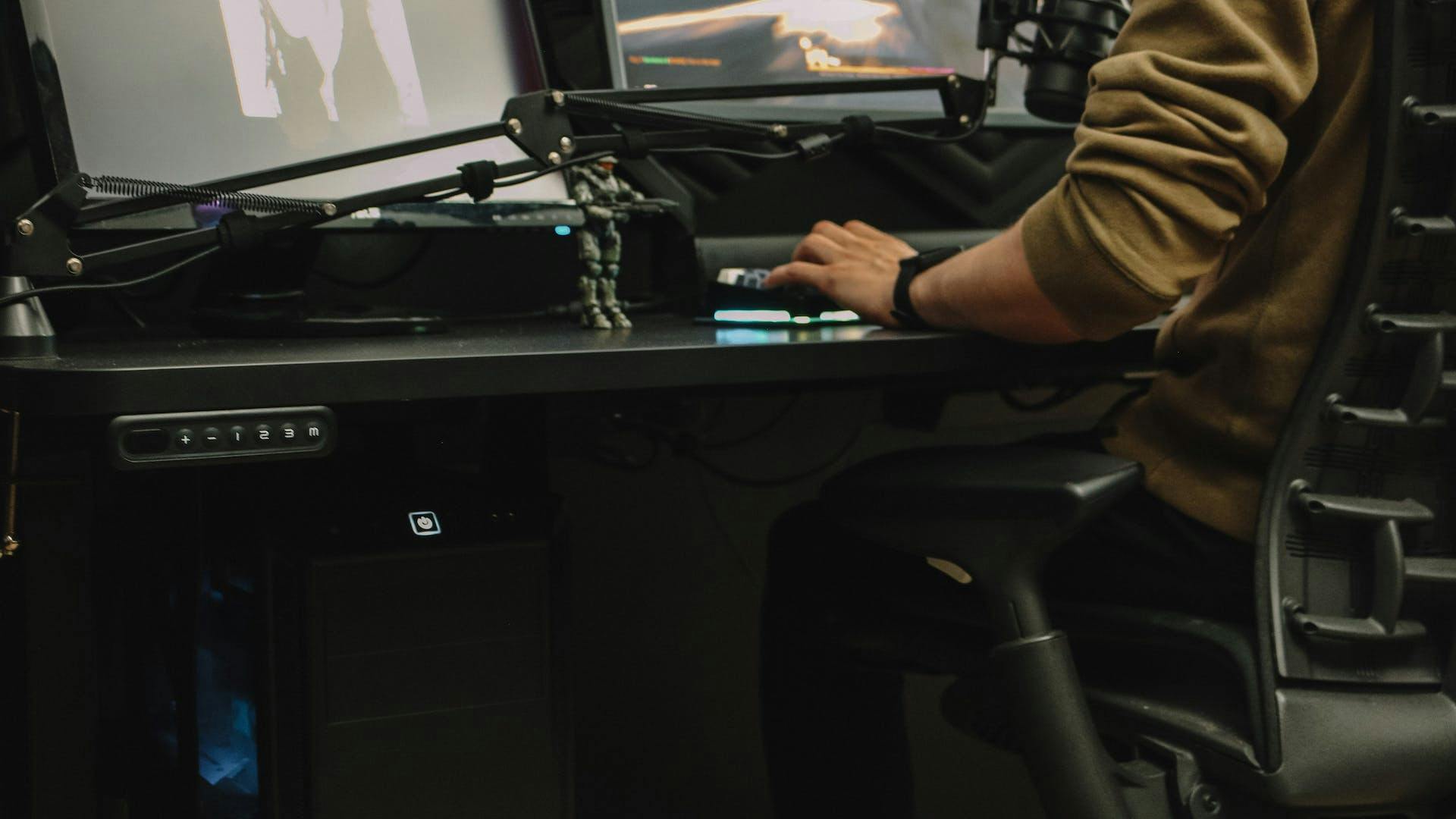 Nahansicht auf einen Gaming Tisch von LeetDesk an dem eine Person sitzt und unter dem keine Kabel im Beinbereich zu sehen sind