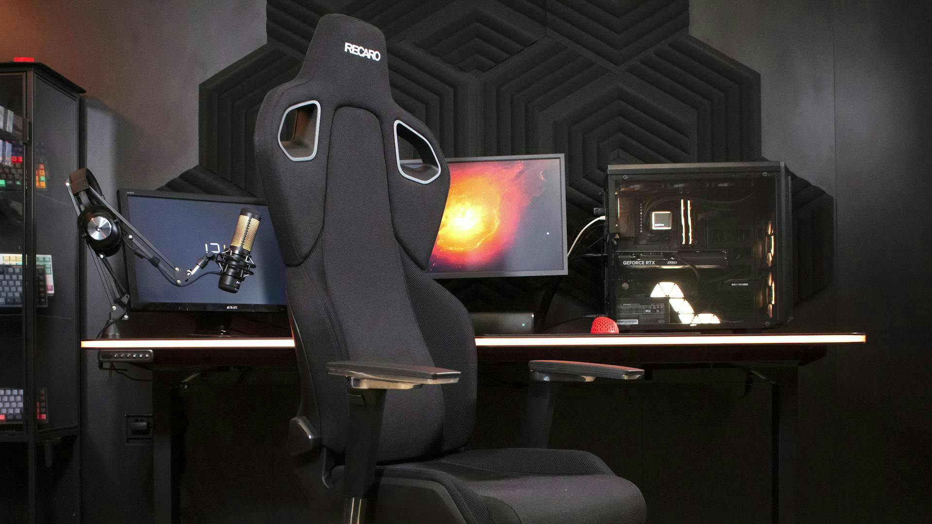 Ein Gaming Stuhl von Recaro steht vor dem LeetDesk AURA mit Streaming Setup.