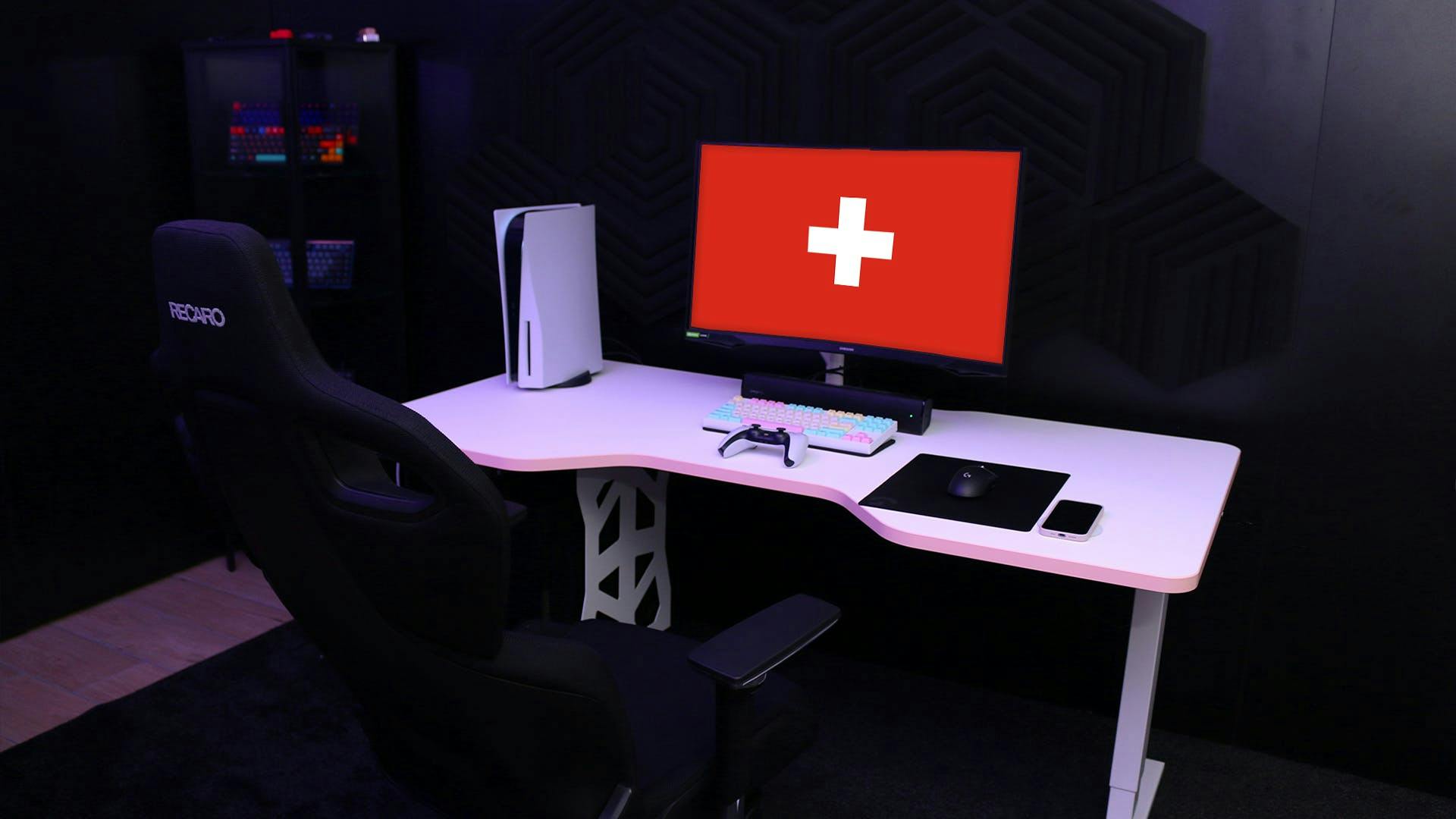 Białe biurko LeetDesk Light w czarnym pokoju z flagą Szwajcarii na monitorze.