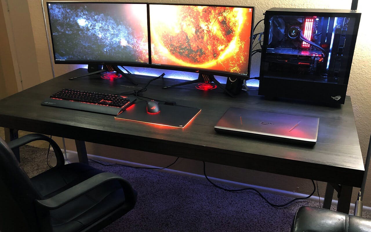 A minimalist black gamer desk with PC on it