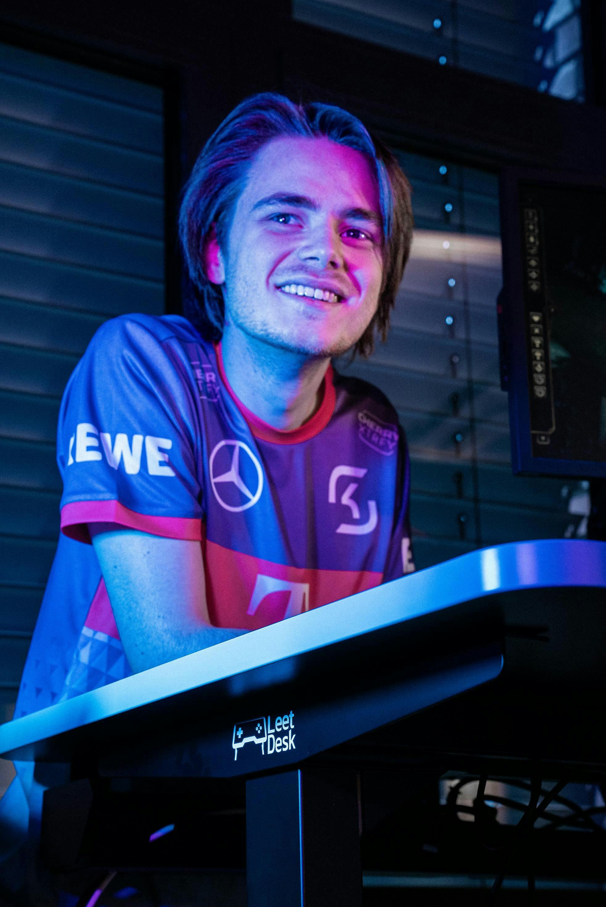 An esports athlete from SK Gaming leans on a LeetDesk gaming desk.