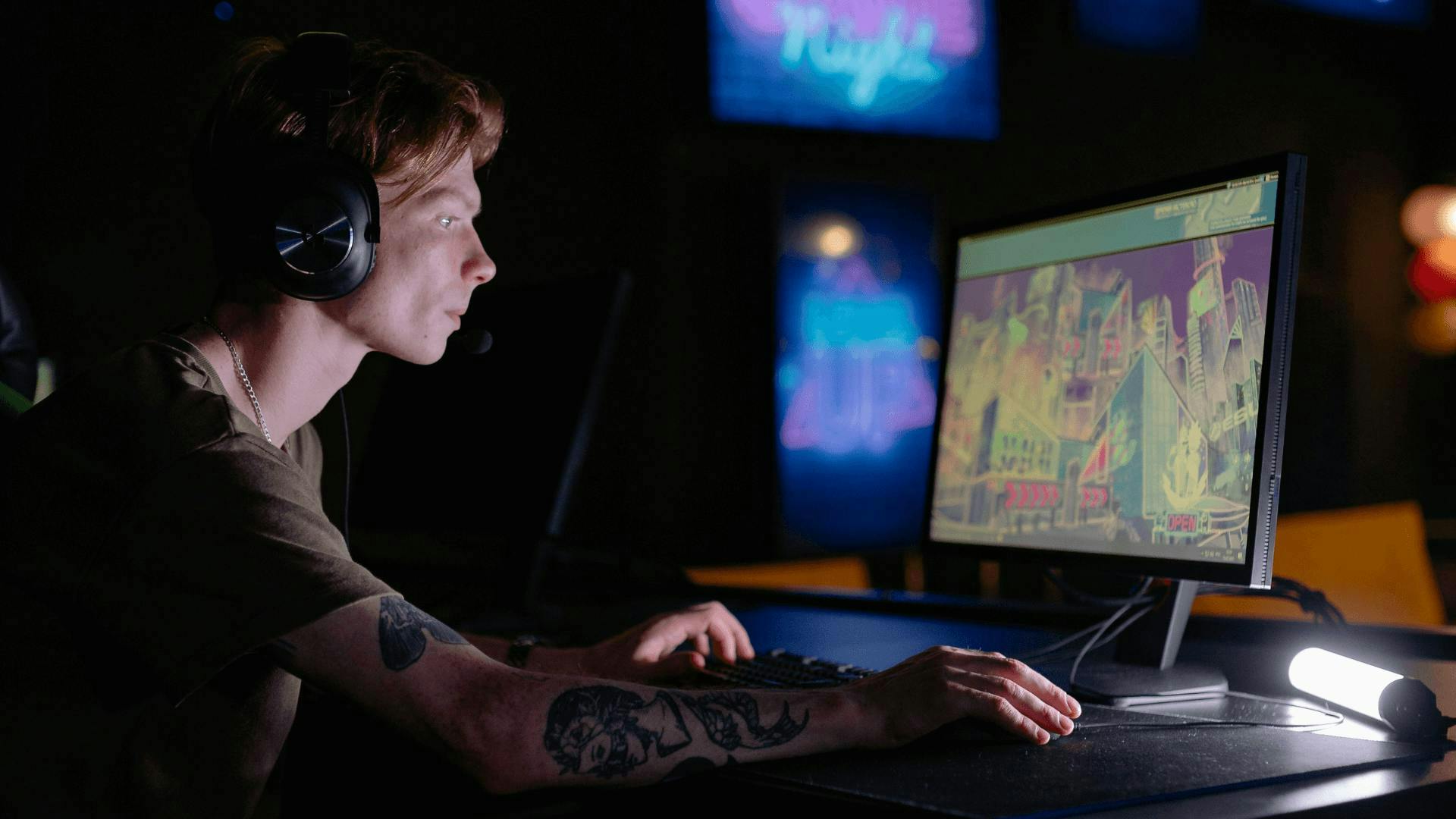 Ein Mann, der in einem dunklen Raum auf einen Gaming Monitor schaut