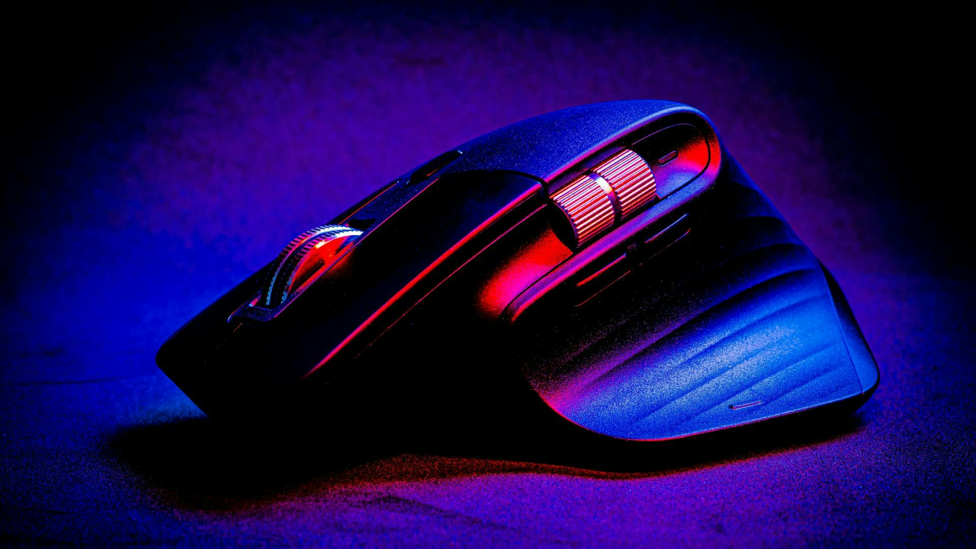 Eine rot und blau leuchtende, kabellose und außergewöhnlich geformte LED Gaming Maus mit Mausrädern an der Seite