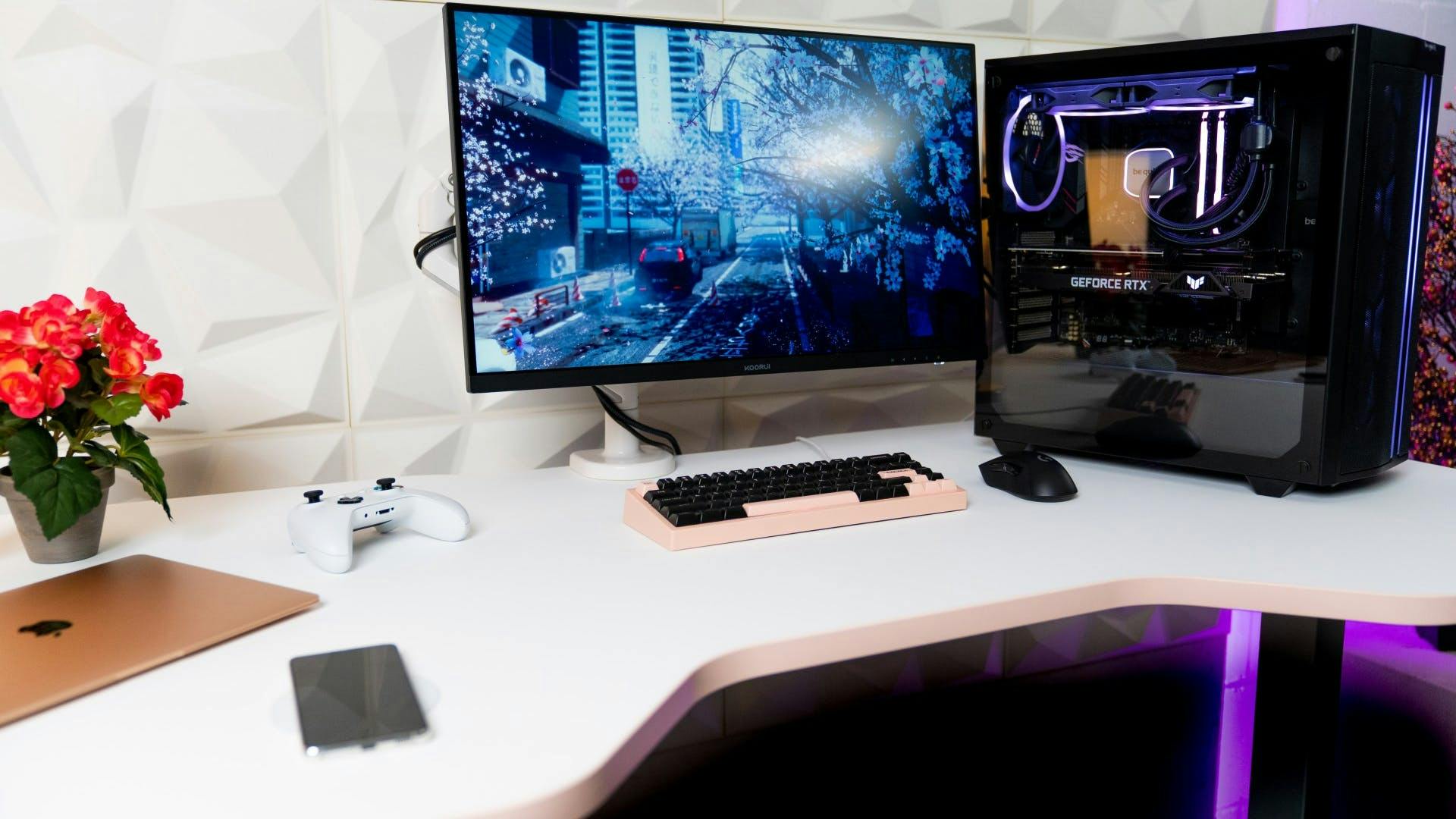 In einem weiß gehaltenen, schlichten Gaming Setup mit weißem LeetDesk, steht ein Gaming PC mit lila LED Leuchten, einem Monitor, einem Laptop, Controller und Handy 